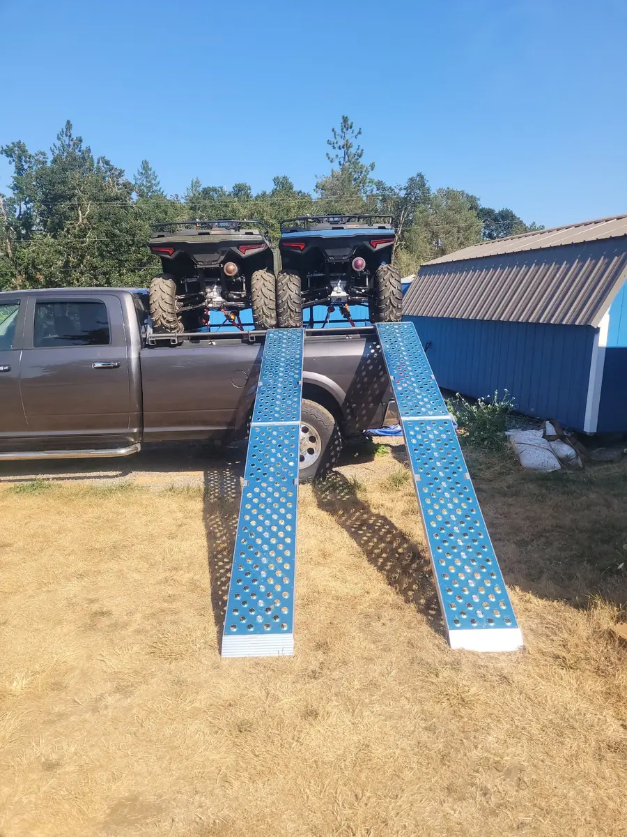 Aluminum ATV rack on a pickup with two loading ramps down to the ground