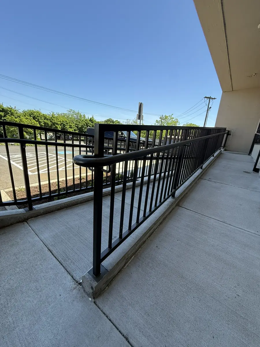 Black steel ramp handrail along a storefront walkway