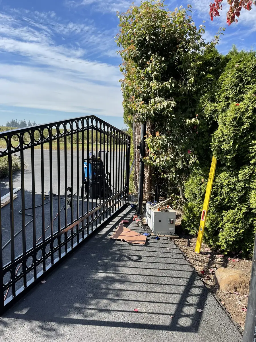 Arched black steel driveway gate with a row of rings along the top