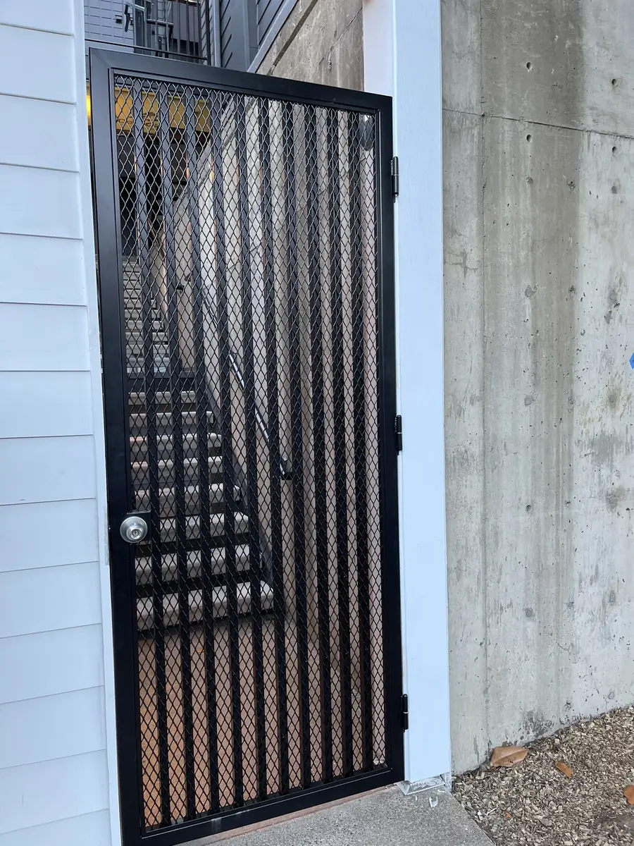 Black steel security door with expanded mesh at a stairwell entry